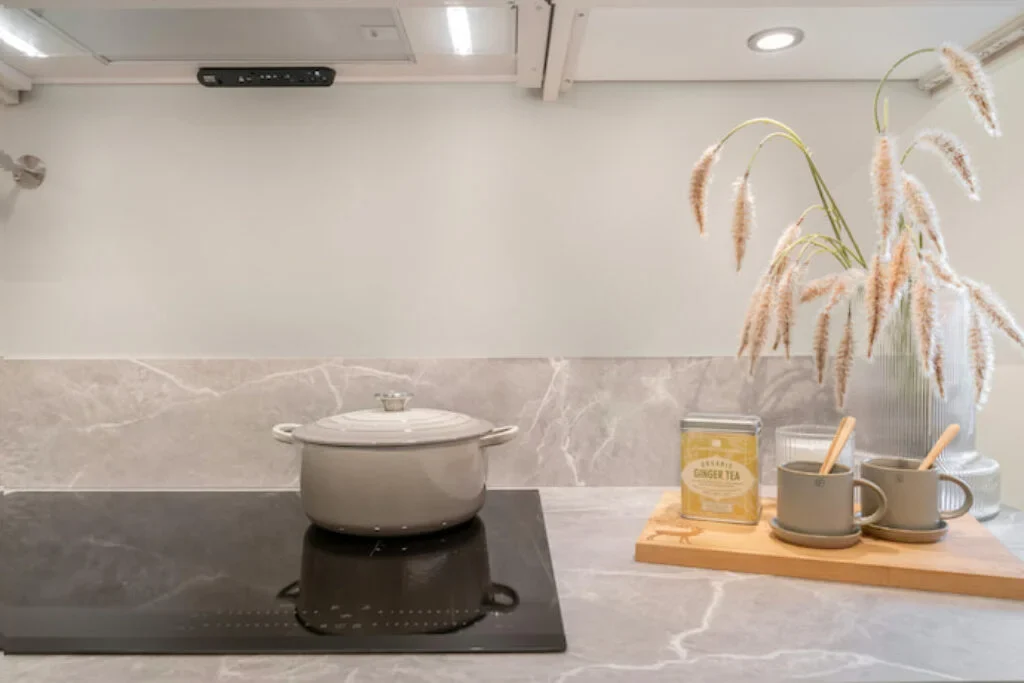 Um melhor cooktop por indução com uma panela em cima e ao lado de alguns itens de cozinha.