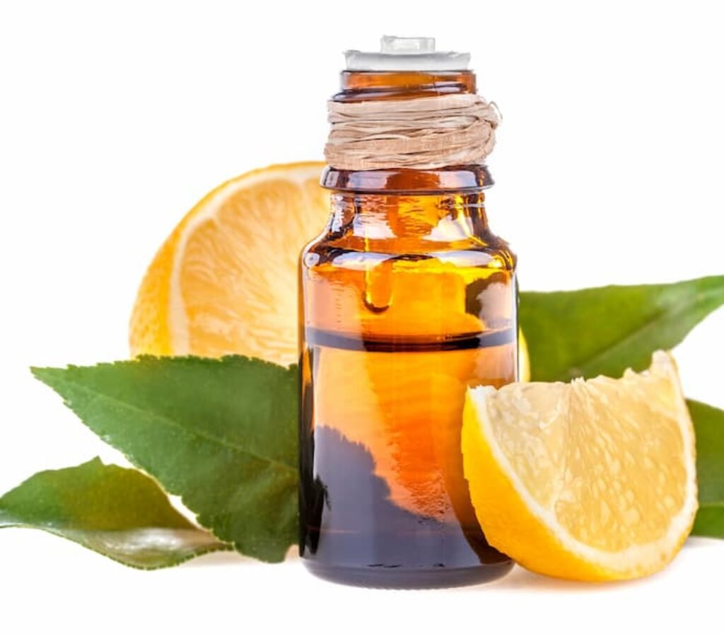 Uma embalagem de óleos essencial, folhas de laranjeira e pedaços de laranja.