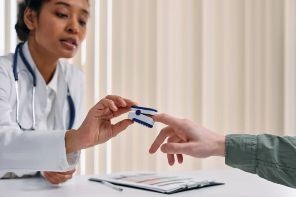 Uma médica colocando um oxímetro no dedo de um paciente.