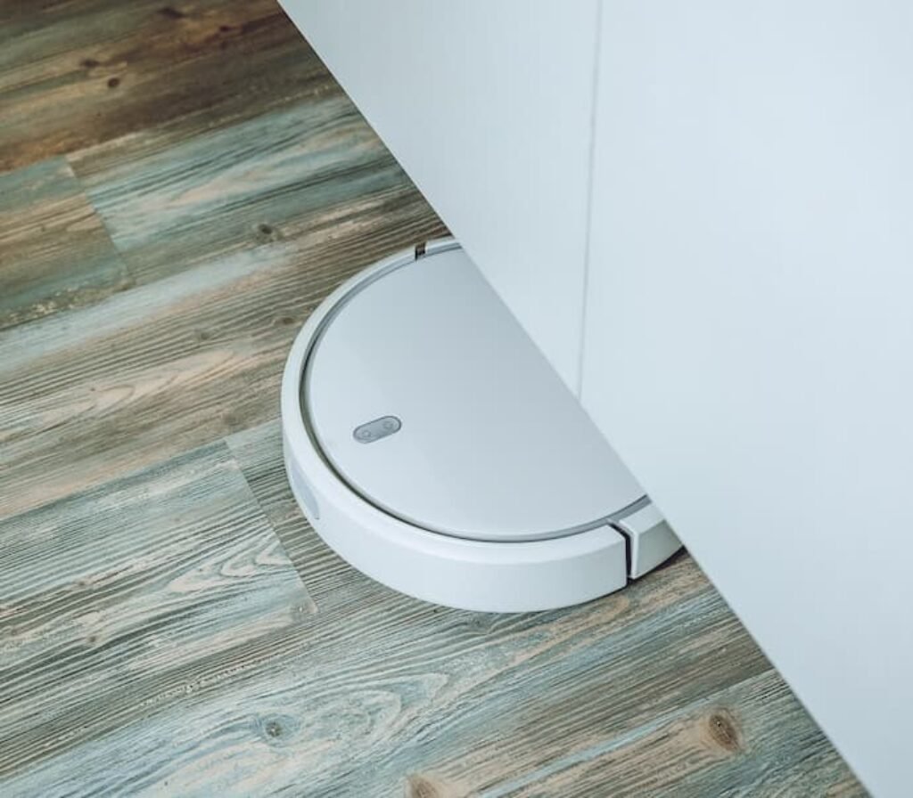 Um aspirador robô aspirando debaixo de uma mesa.