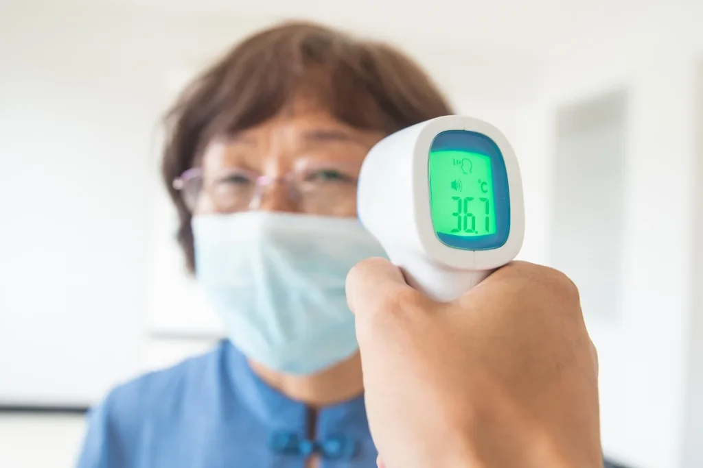 Uma pessoa medindo a temperatura de outra pessoa, com um melhor termômetro digital.