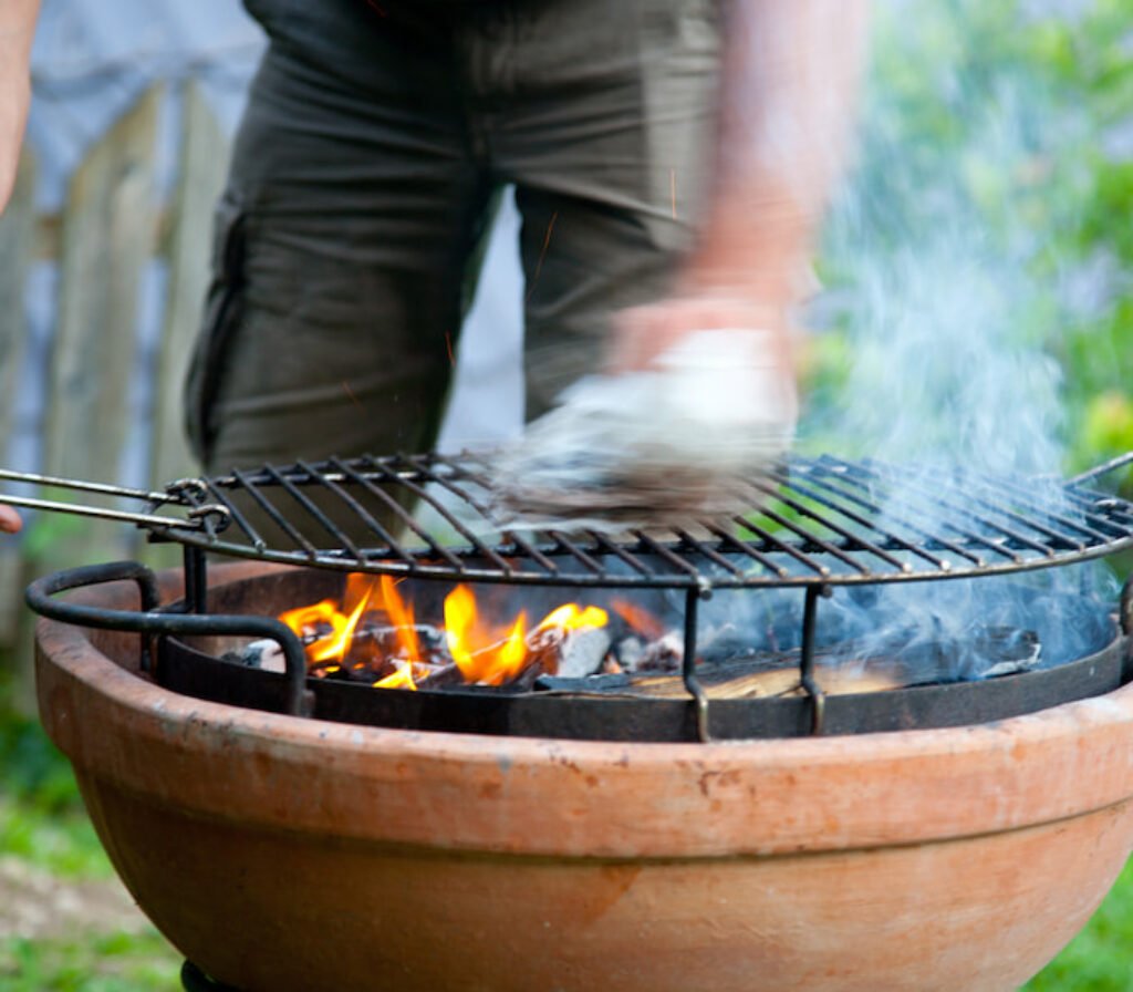 Uma pessoa fazendo churrasco em um jardim.