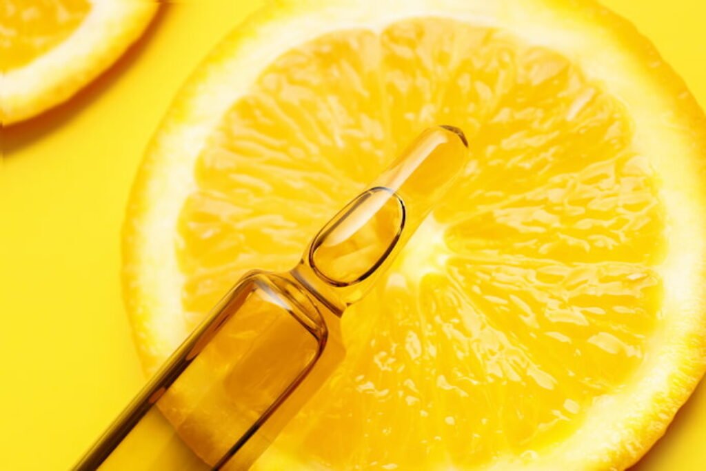 Ampola de vitamina com uma laranja ao fundo.