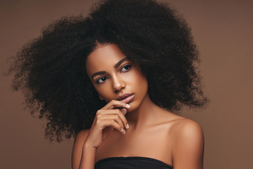 Mulher com cabelo crespo em um fundo marrom.