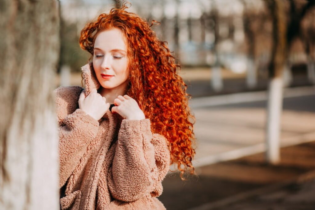 Mulher com cabelo cacheado ruivo.