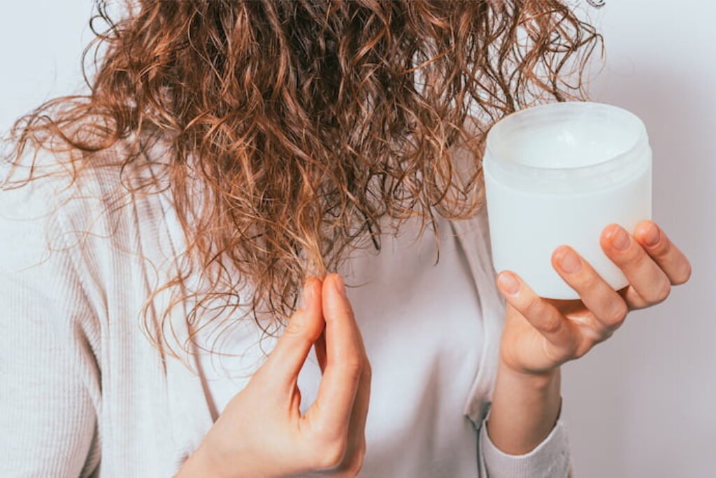 Mulher de cabelo ondulado aplicando ativador de cachos.