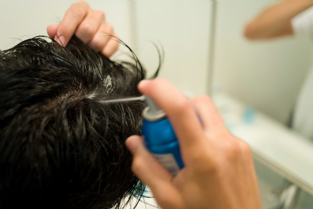 Homem aplicando tônico no cabelo.