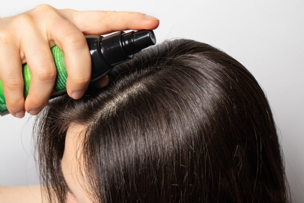 Mulher de cabelo castanho aplicando tônico capilar de crescimento.