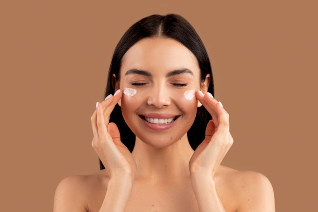 Mulher sorrindo aplicando creme no rosto.