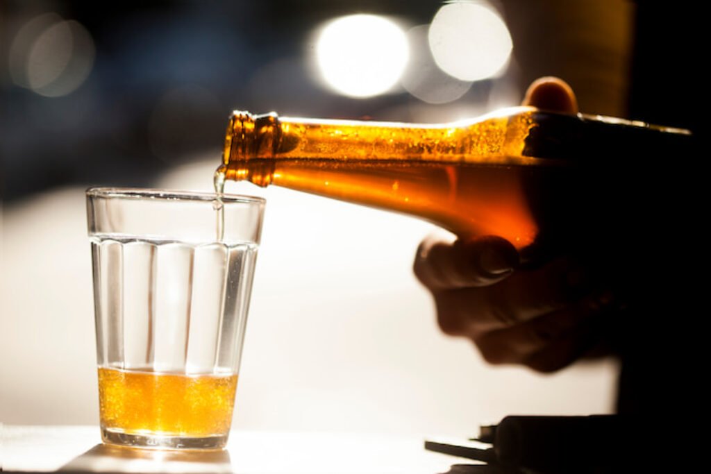 Pessoa colocando cerveja em um copo americano.