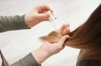 Pessoa aplicando reparador nas pontas do cabelo de uma mulher.