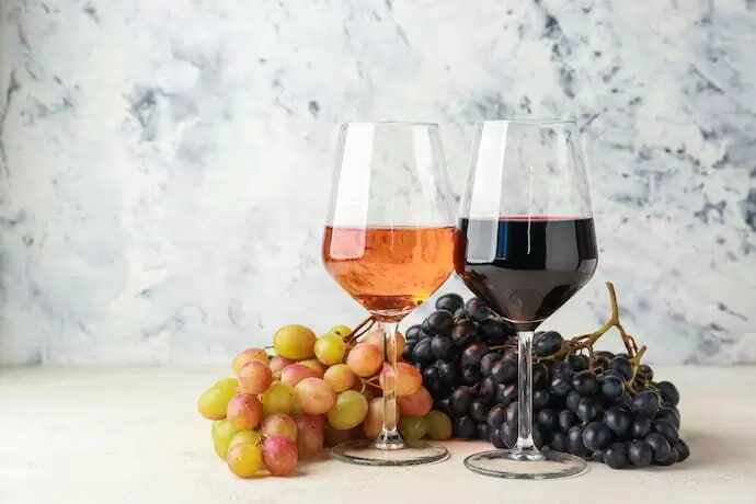 Duas taças de vinho ao lado de uvas.