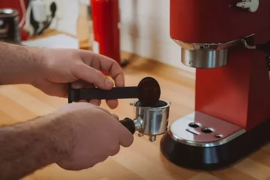Uma pessoa colocando pó de café em uma cafeteira.