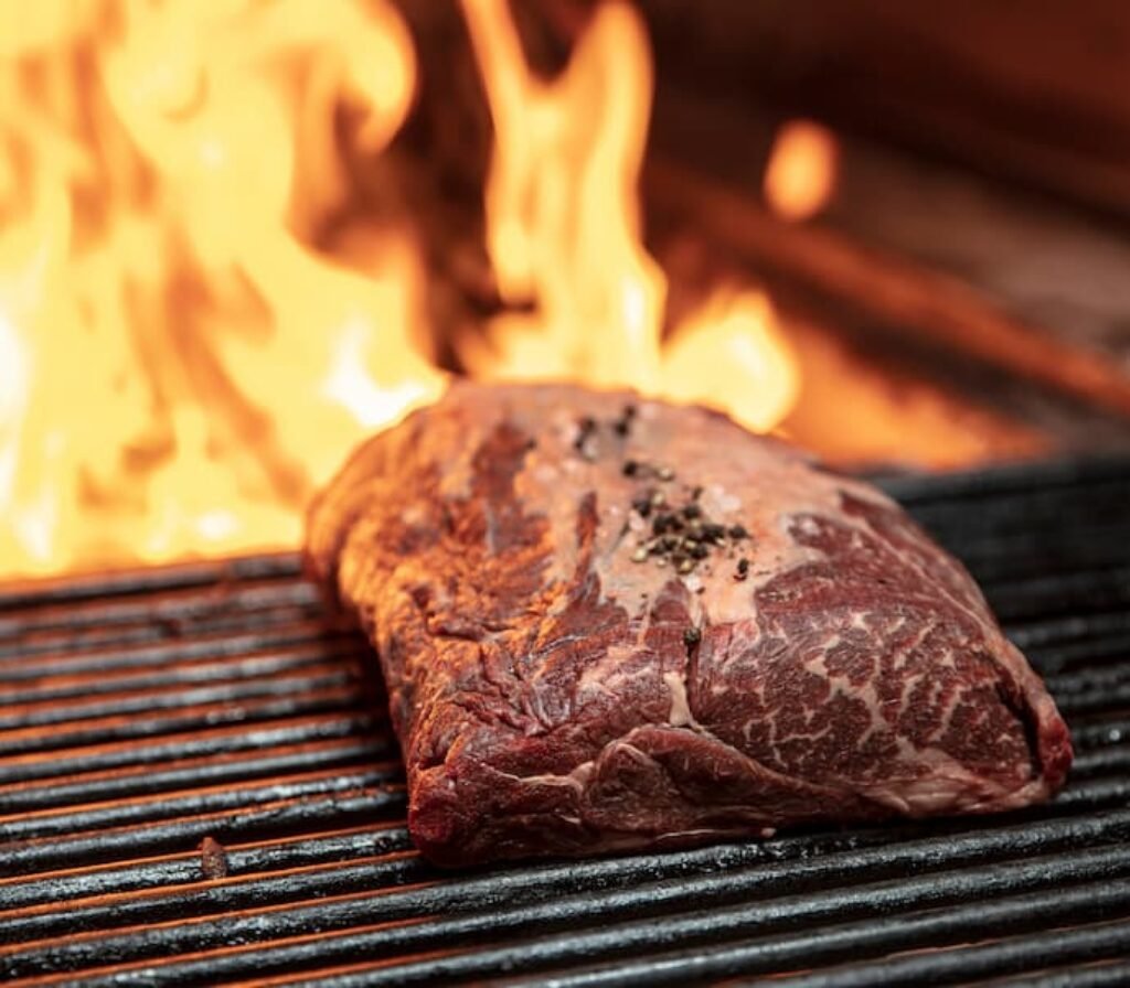 Uma carne sendo assada em uma melhor churrasqueira a carvão profissional