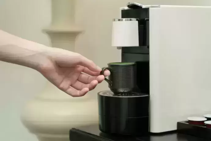 Uma pessoa colocando uma xícara na melhor cafeteira elétrica.