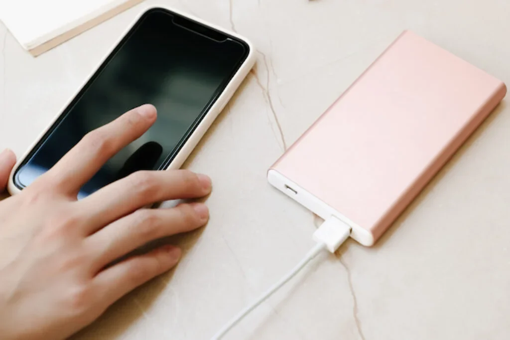 Um carregador, um cabo USB e um celular em cima de uma mesa.