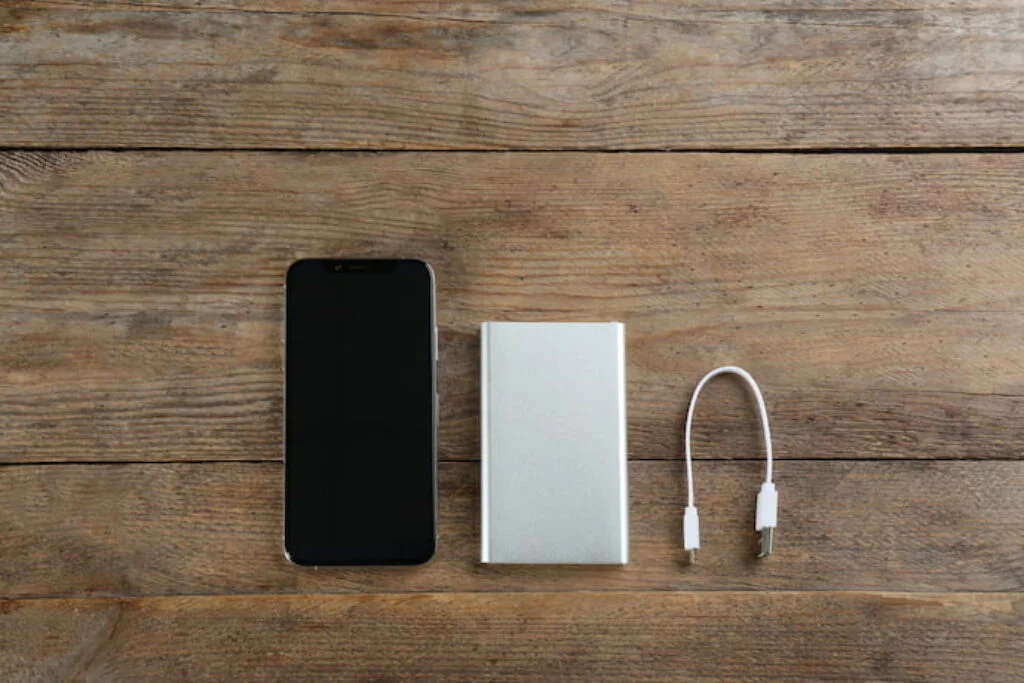 Um melhor carregador portátil ao lado de um celular e de um cabo USB.