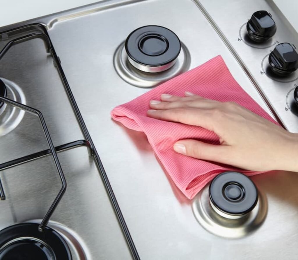 Uma pessoa limpando a mesa de um melhor fogão inox.