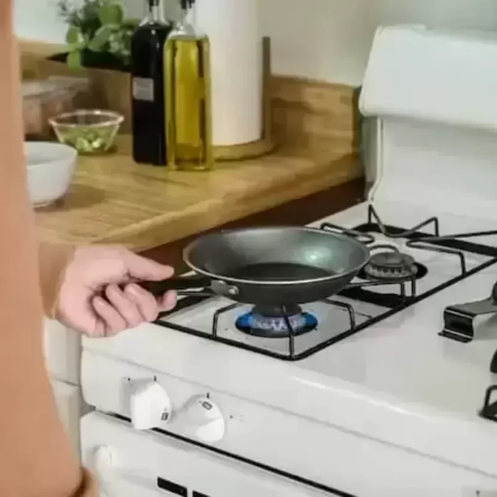 Uma frigideira pequena sendo aquecida em um fogão da linha branca.