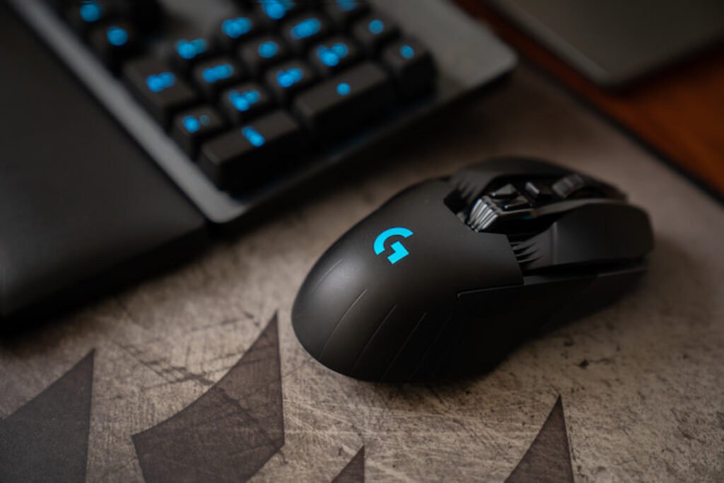 Mouse gamer ao lado de um teclado preto e azul. 