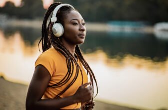 Mulher de headphones correndo na beira de um lago.