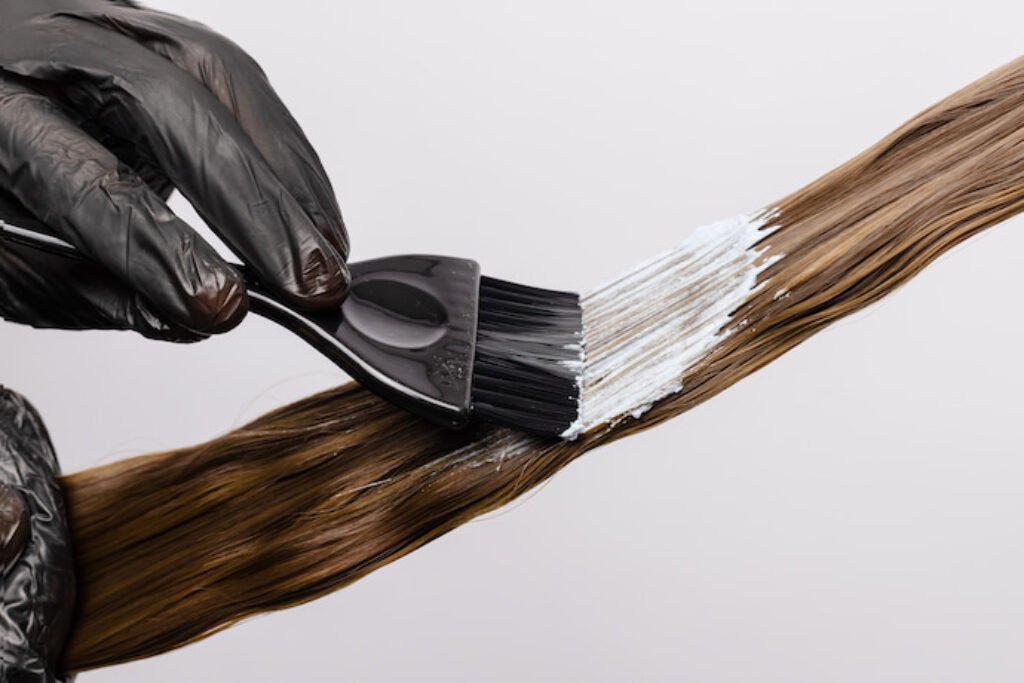 Pessoa passando creme em um cabelo com pincel.