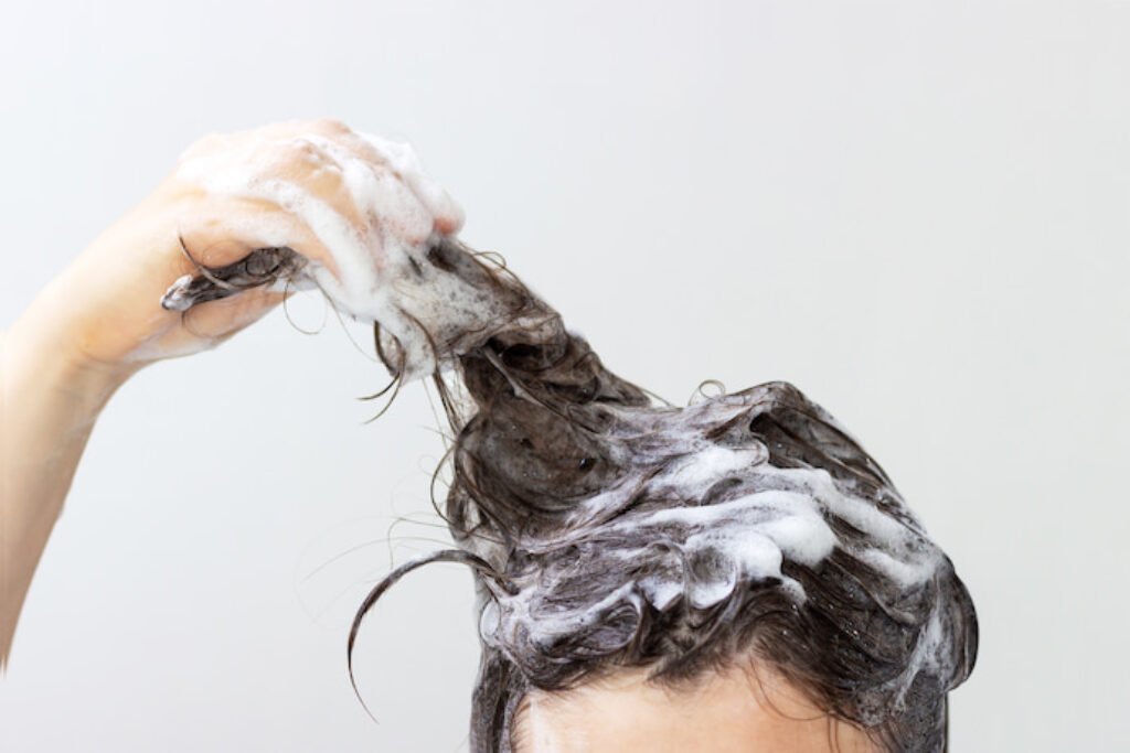 Pessoa puxando mecha de cabelo cheio de shampoo. 