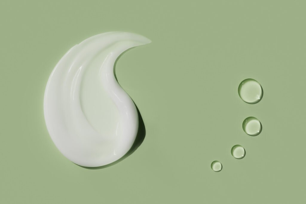 Rastro de creme e quatro gotas em uma superfície verde.