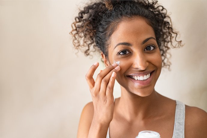 Mulher sorrindo e fazendo skincare.