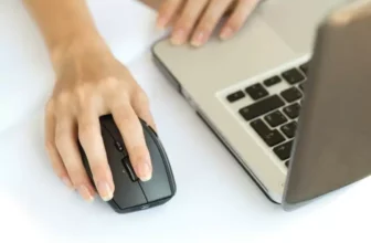 Mouse sem fio ao lado de um notebook.