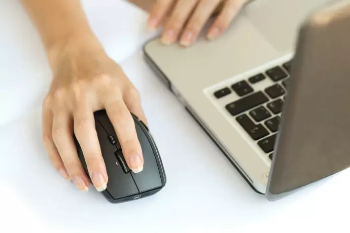 Mouse sem fio ao lado de um notebook.