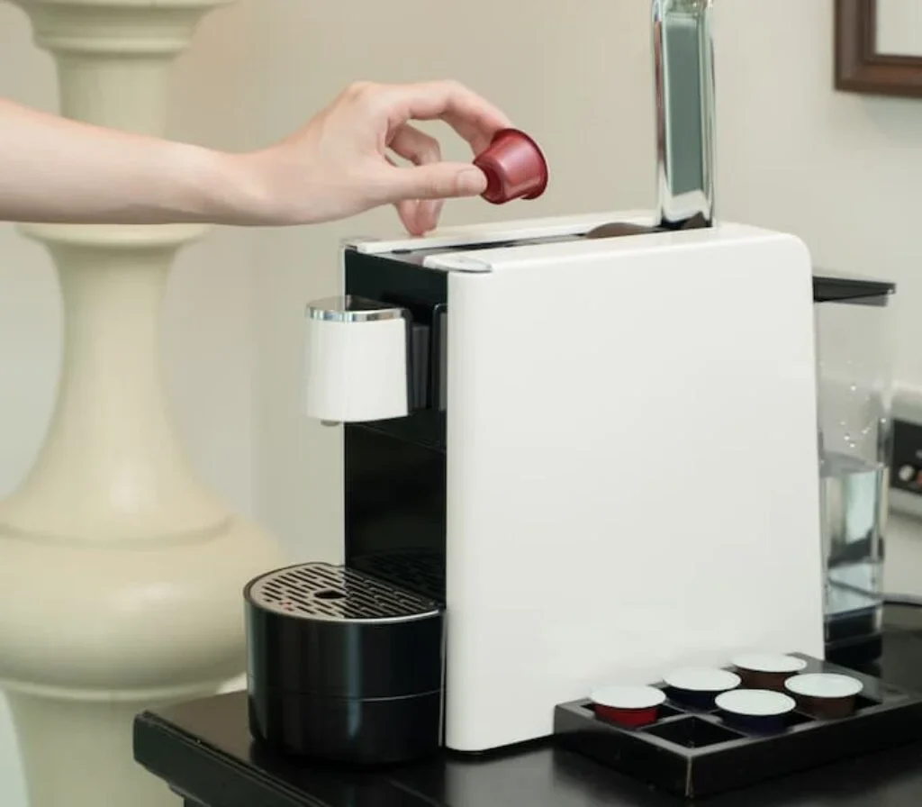 Uma pessoa coloca uma cápsula em uma máquina de café.