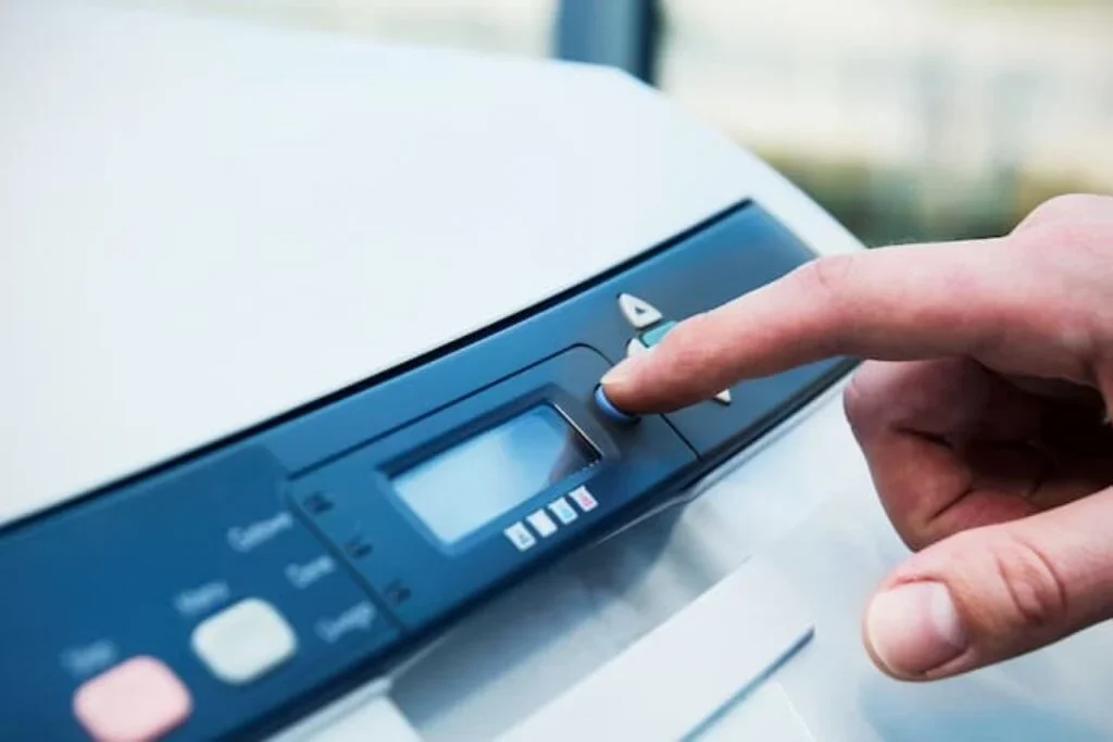Uma pessoa clica no botão de um painel de uma melhor impressora laser.