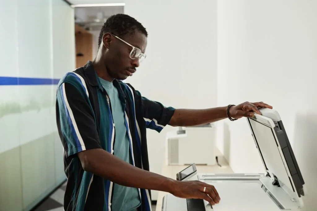 Um homem usando o scanner de uma melhor impressora para escritório.