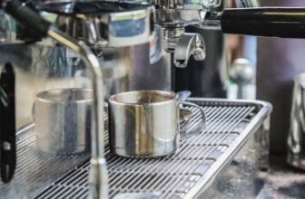 Uma melhor cafeteira expresso de aço inox enchendo de café uma xícara de metal.