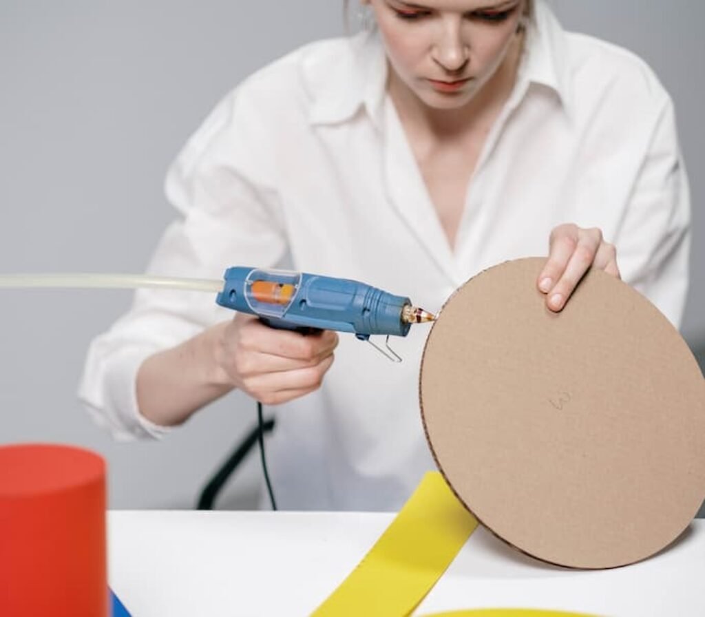 Uma mulher usa uma melhor pistola de cola quente para colar um papelão.