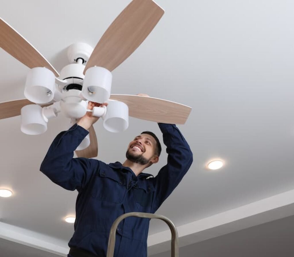 Um técnico instalando um ventilador de teto em uma sala.