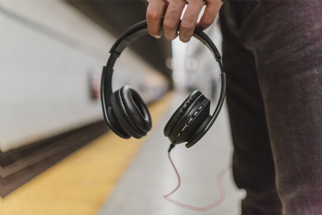 Pessoa segurando um fone de ouvido em uma estação de metrô.