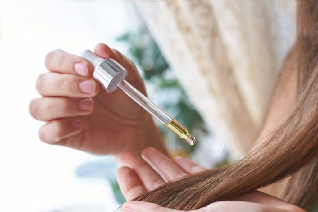 Mulher pingando óleo no cabelo com um conta gotas.
