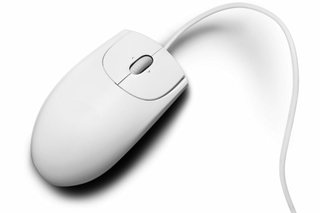 Mouse com fio branco em um fundo predominantemente branco.