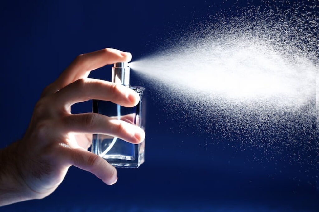 Pessoa borrifando perfume em um fundo azul.