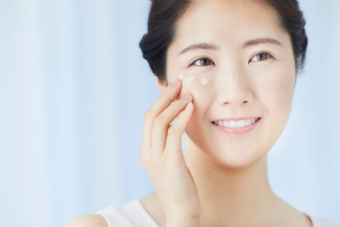 Mulher passando corretivo no rosto.