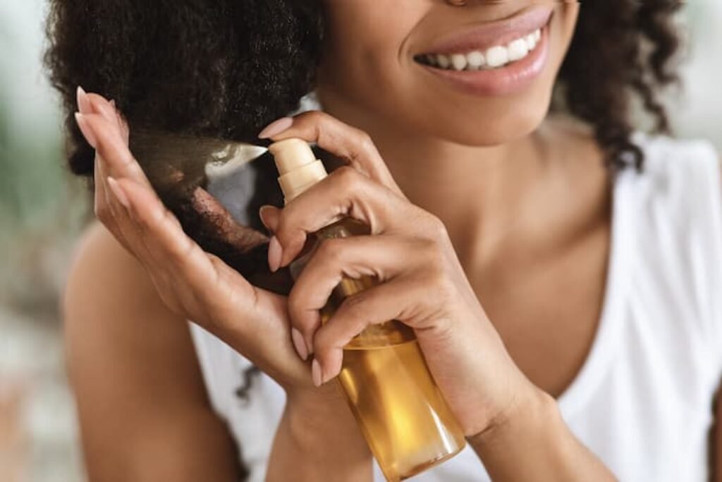 Mulher de cabelo cacheado passando spray. 