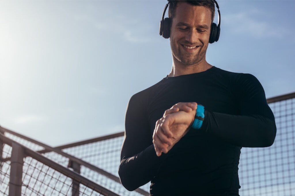Rapaz de fone de ouvido sorrindo e olhando para o smartwatch.