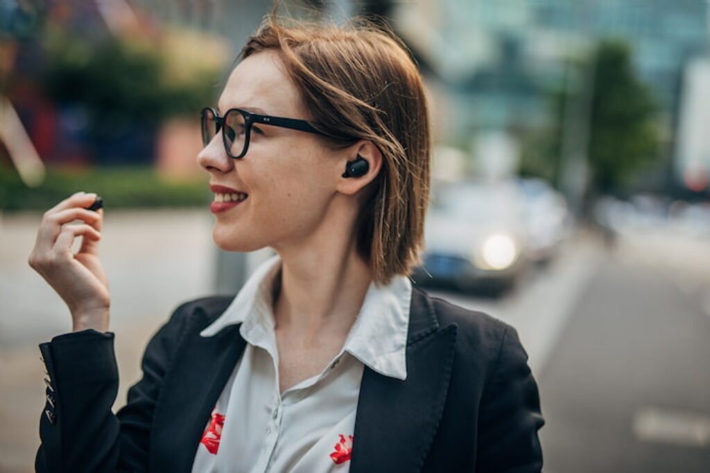 Mulher de cabelo curto ouvindo música com fone intra-auricular. 