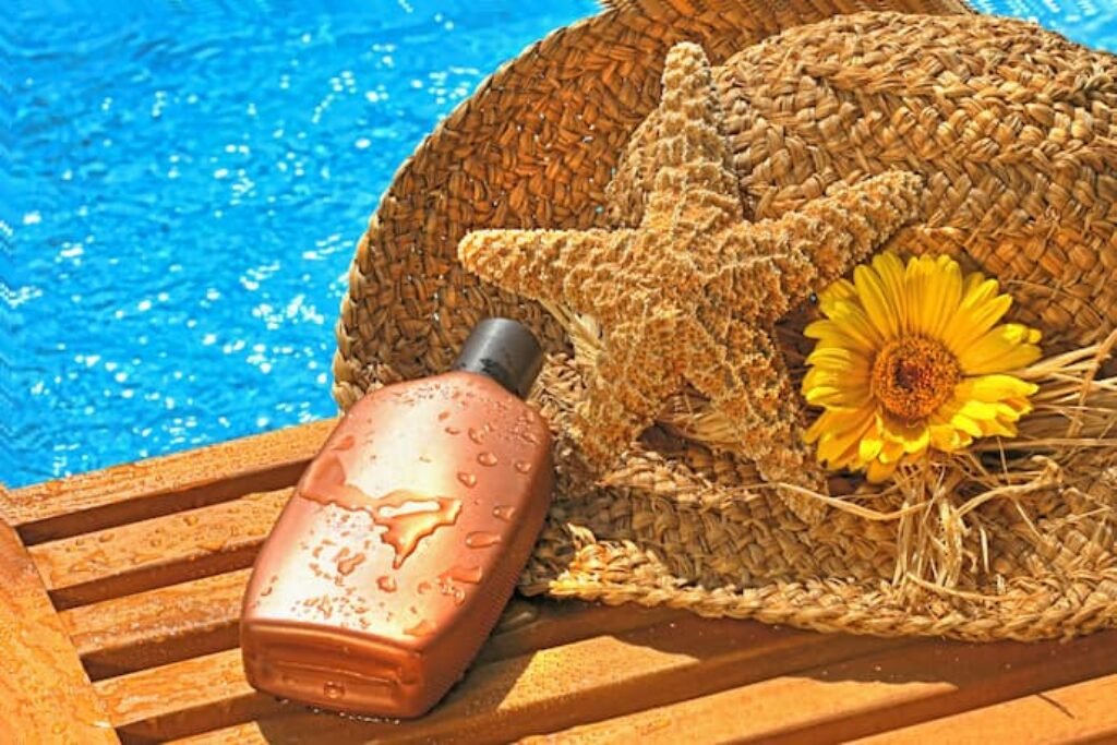 Bronzeador ao lado de uma estrela do mar e de um chapéu.