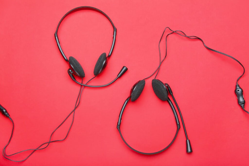 Dois headphones pretos em um fundo rosa.