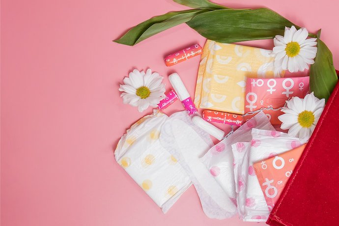 Absorventes e flores em um fundo rosa.