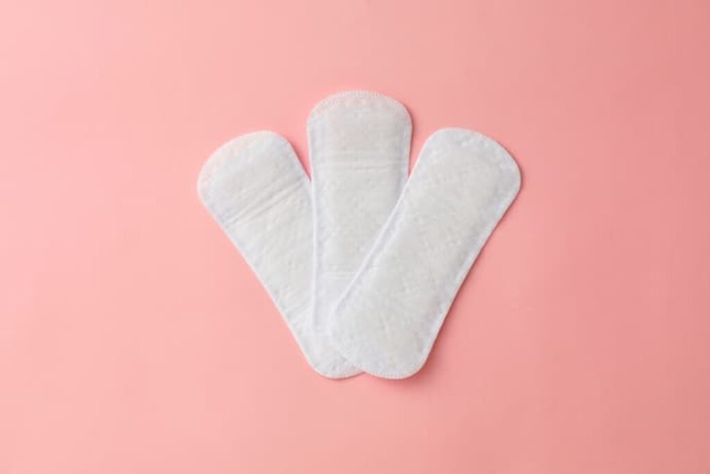 Três absorventes em um fundo rosa.